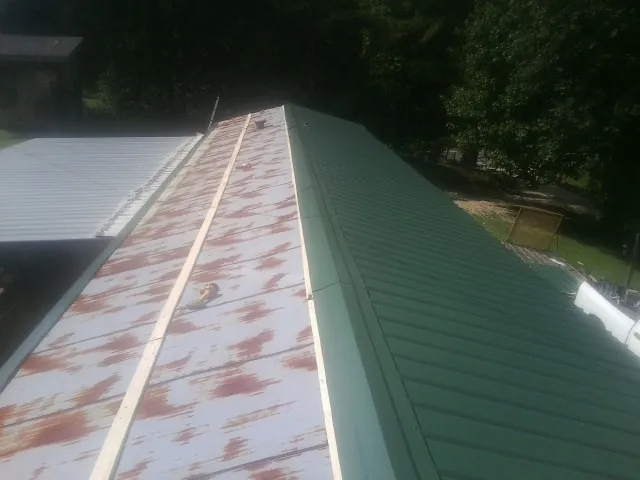 Old rusted panels beside newly installed green metal roofing — Wind Damage Roof Repair by Roofing Brothers in Henryetta