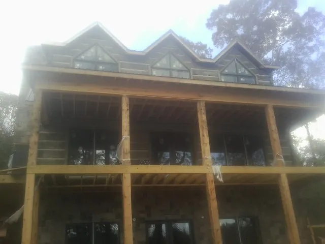 Dormers and porch framing on a large log home under construction — Roof Coating work by our crew in Henryetta