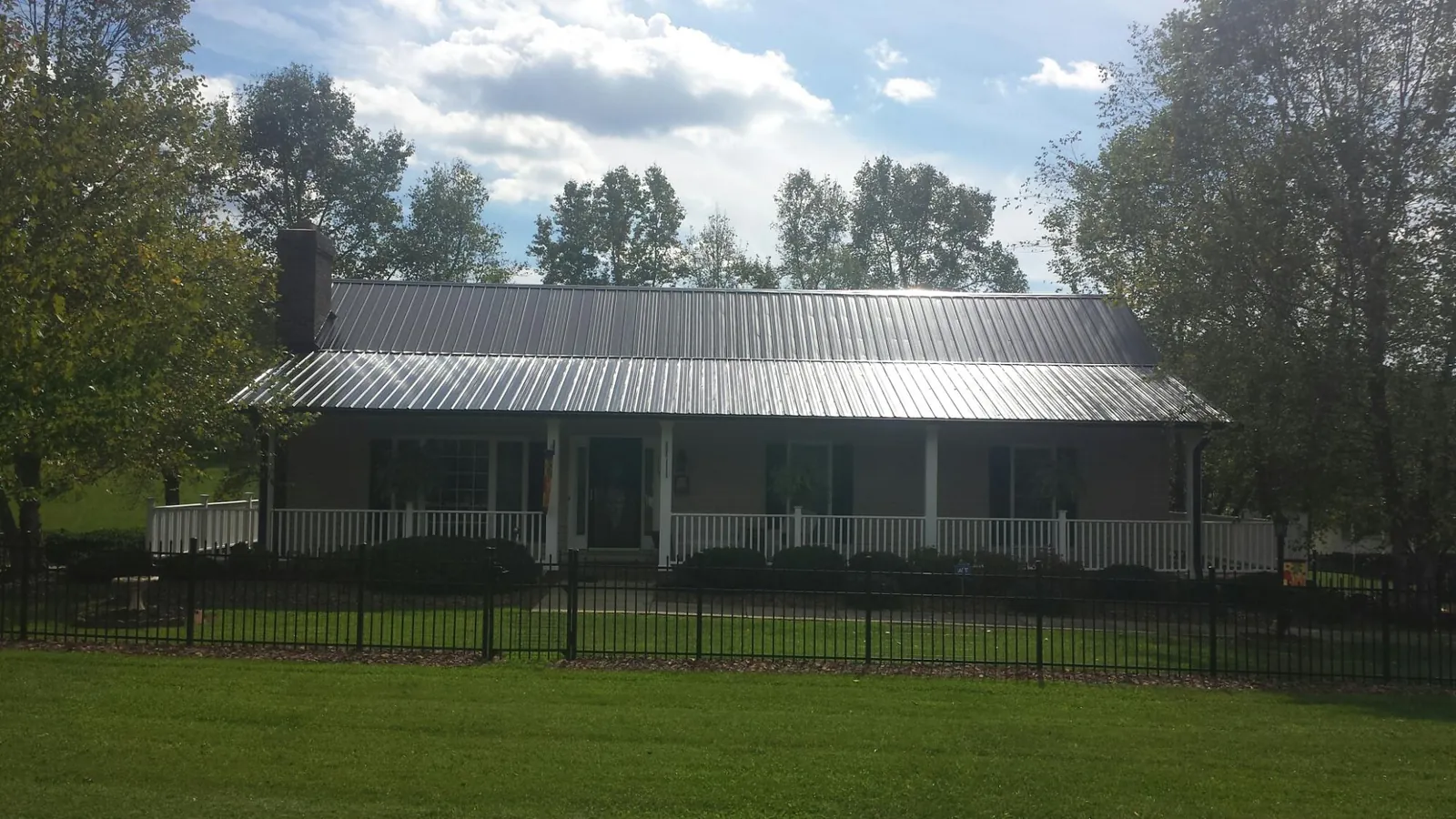 Gray metal roof on a brick ranch with a full width front porch — Gutter Guard Installation work by our crew in Henryetta