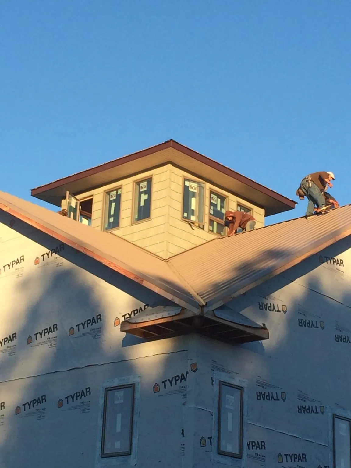 Roofers working around a rooftop cupola on a new metal roof at sunset — Roof Waterproofing in Henryetta by Roofing Brothers